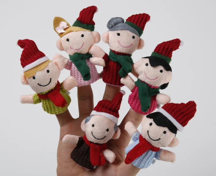 Set of six knitted finger puppets in Christmas-themed outfits on a hand against a white background.