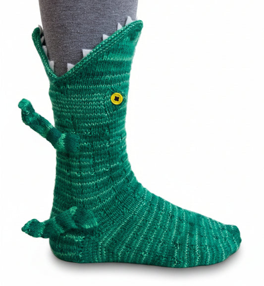 Green crocodile-themed sock on a person's foot with a neutral background