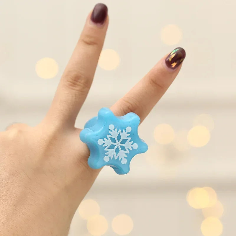 Blue snowflake-shaped ring on a finger with a blurred light background