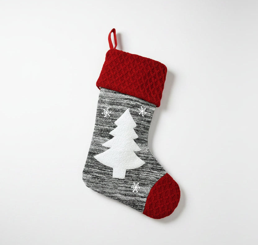 Christmas stocking with red top and gray body featuring a white tree design, hanging on a white background.