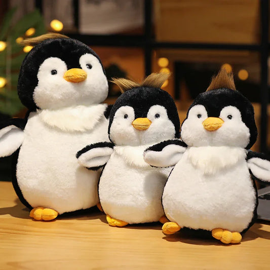 Three plush penguins sitting together on a wooden surface with a blurred background.