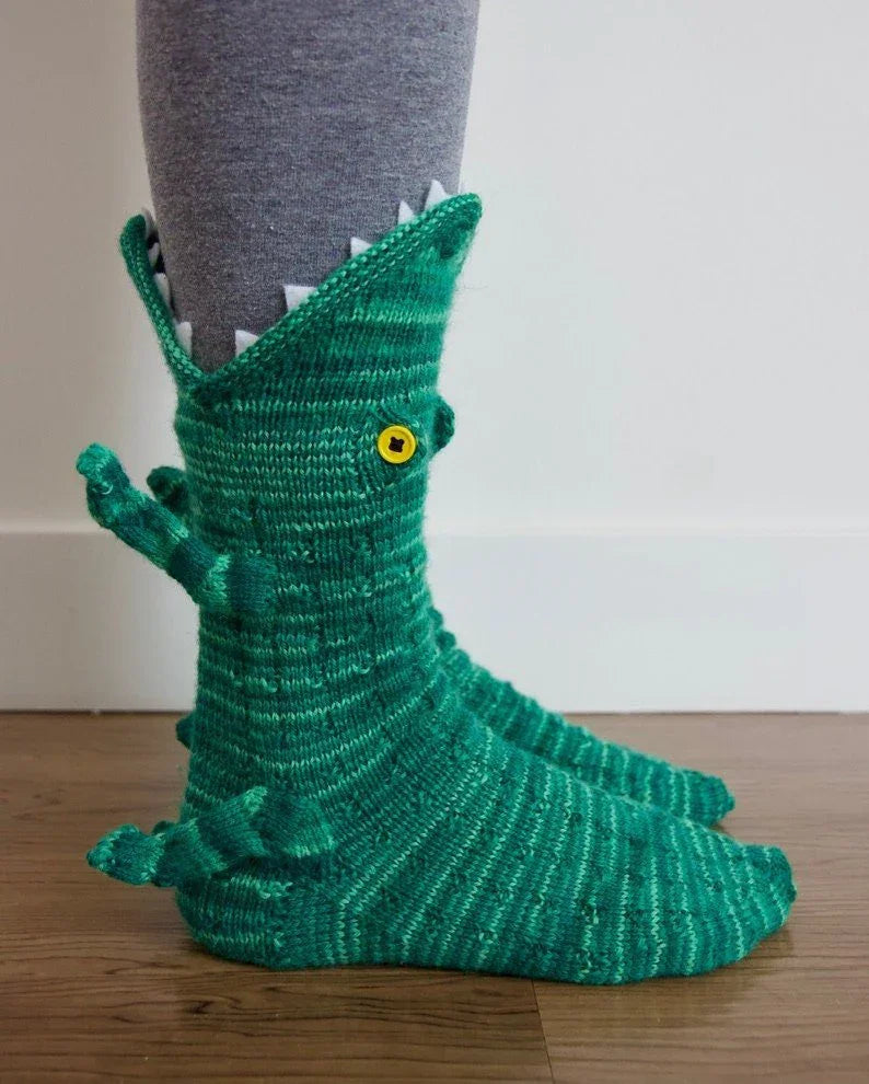 Green crocodile-themed sock on a person's foot with a neutral background