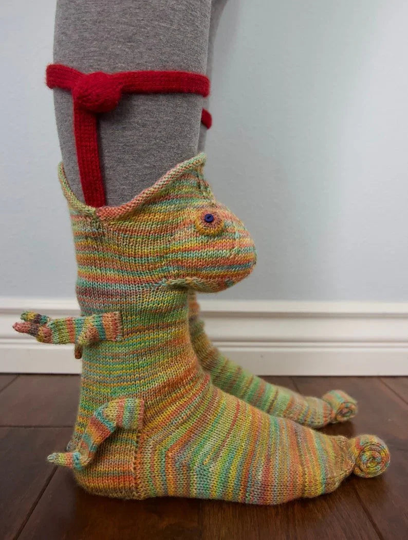 Colorful knitted dragon-shaped slipper on a wooden floor with a plain background