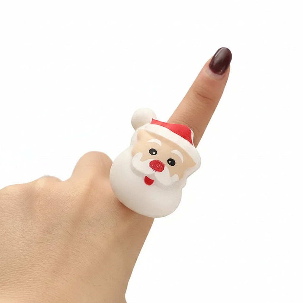 Hand wearing a Santa Claus-shaped ring with a blurred light background